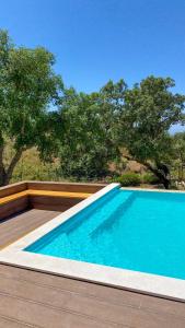 una piscina con terrazza in legno e alberi di Celestial Melides Country House a Melides