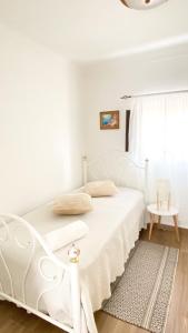 a white bed in a white bedroom with a window at Celestial Melides Country House in Melides