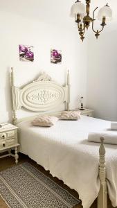 a white bedroom with a white bed and a chandelier at Celestial Melides Country House in Melides