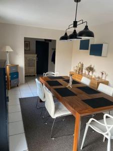 a dining room with a wooden table and white chairs at "La Homerie" Chaumière en pleine nature in Savigny-en-Sancerre +17 photos