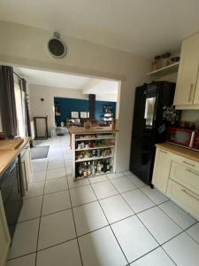 a kitchen with a black refrigerator and a white tile floor at "La Homerie" Chaumière en pleine nature in Savigny-en-Sancerre
