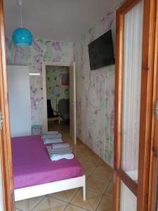 Habitación pequeña con cama con sábanas moradas. en Appartamento Via Pitagora, en Scalea