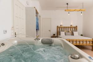 a bath tub filled with water in a room with a bed at Aqua Naxos Apartments & Suites in Naxos Chora