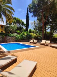 een zwembad met ligstoelen en een houten terras bij Casa Rural El Borbullón in Teror