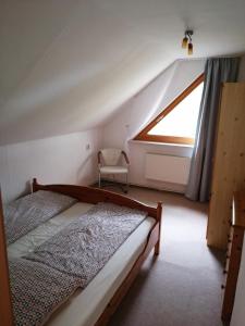 ein Schlafzimmer mit einem Bett, einem Fenster und einem Stuhl in der Unterkunft Reiterhof Groß Stubben in Poseritz