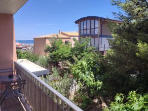 - un balcon d'une maison avec des arbres, une table et un bâtiment dans l'établissement T3 45M2, Cap d'Adge,Secteur Falaise,4-6 pers, Clim, Fibre - WIFI, 100m plage, au Cap d'Agde