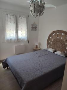 a bedroom with a large bed and a chandelier at T3 45M2, Cap d'Adge,Secteur Falaise,4-6 pers, Clim, Fibre - WIFI, 100m plage in Cap d'Agde