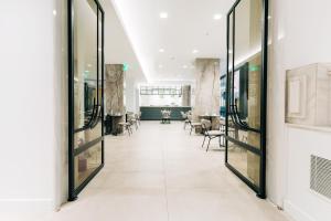 un pasillo con puertas de cristal y sillas en un edificio en Athinais Hotel, en Atenas