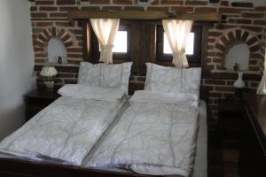 łóżko z białą pościelą i poduszkami w sypialni w obiekcie Guest House Shapkova Kushta w mieście Delchevo