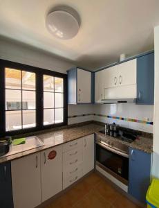 una cocina con armarios y ventanas de color azul y blanco en Long Beach Surf House en Corralejo
