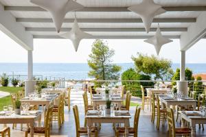 um restaurante com mesas e cadeiras com o oceano ao fundo em Istion Club & Spa em Nea Potidaea