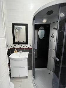 La salle de bains est pourvue d'une douche, d'un lavabo et d'un miroir. dans l'établissement Апартаменты Центр Трускавец, à Trouskavets