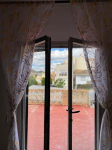 une fenêtre avec des rideaux et une vue sur une cour dans l'établissement Casita Rural La Rosa de la Huerta con chimenea interior, à Monachil