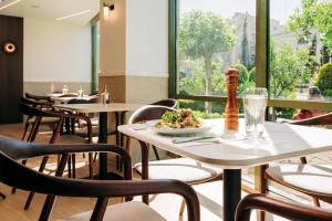 un restaurante con mesas y sillas y un plato de comida en Athinais Hotel, en Atenas