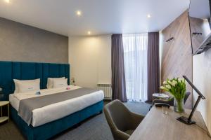 ein Hotelzimmer mit einem großen Bett und einem Schreibtisch in der Unterkunft Ribas Rooms Bila Tserkva in Bila Zerkwa