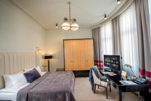 Una habitación de hotel con una cama y un escritorio en una habitación en Astoria Hotel en Leópolis