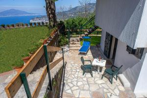 d'une terrasse avec des chaises et une table offrant une vue sur l'eau. dans l'établissement Sorrento Iulia Cottage, à Torca
