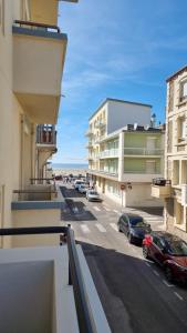 un balcone con vista su una strada con auto parcheggiate di Appartement BERCK à deux pas de la plage a Berck-sur-Mer