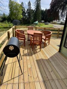 a wooden deck with a table and chairs and a grill at The Astoria in Dunoon