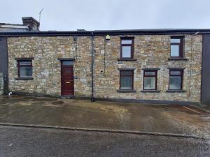 a brick building with a red door and windows at Perfect Location 3 Bed Serviced apartment with Bike Storage for BPW. Close to Brecon Beacons in Merthyr Tydfil