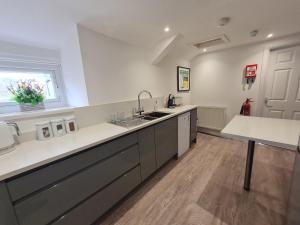 a large kitchen with white counters and a sink at Perfect Location 3 Bed Serviced apartment with Bike Storage for BPW. Close to Brecon Beacons in Merthyr Tydfil