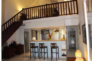 a living room with a staircase and bar stools at La Valentine Résidence La Plantation Sainte Marthe in Saint-François