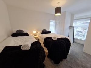 a bedroom with two beds with black and white sheets at Perfect Location 3 Bed Serviced apartment with Bike Storage for BPW. Close to Brecon Beacons in Merthyr Tydfil