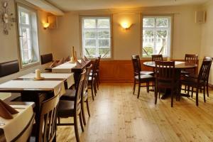 a dining room with tables and chairs and windows at Pension Webstuhl in Deizisau