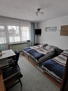 a bedroom with two beds and a table and a desk at Międzyzdroje ul Nowomyśliwska 60 in Międzyzdroje