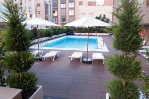 a pool with chairs and umbrellas in a city at Apartamentos Juan Bravo in Madrid