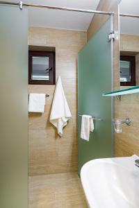een badkamer met een douche, een wastafel en een spiegel bij Epico Seafront & Garden Apartments in Olimp