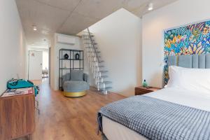 a bedroom with a bed and a chair and a staircase at Bemyguest - Loft Guest House Jardim das Mães Charming in Viseu