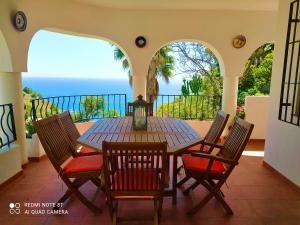 a table and chairs on a balcony with the ocean at House in a cove Almunecar in Almuñécar