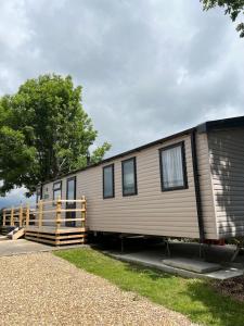 un gran remolque de metal con una valla y un árbol en Sunnycott Caravan Park, en Cowes