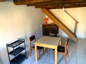 einen Tisch und Stühle in einem Zimmer mit einer Decke in der Unterkunft Petite maison lorraine avec cheminée et jardin in Saint-Mihiel