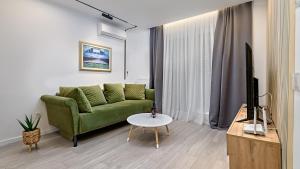 Apartman Nostra 1 في زغرب: غرفة معيشة مع أريكة خضراء وتلفزيون