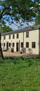 a large white building with a tree in front of it at 1 Barge Cottage in Narborough