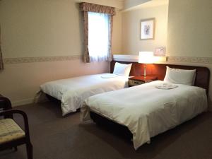 a hotel room with two beds and a window at Ueno Terminal Hotel in Tokyo