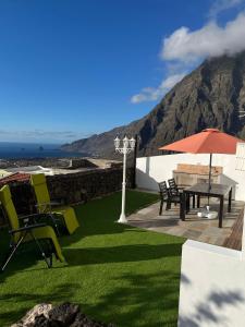 een patio met een tafel en stoelen en een parasol bij CASA PACO Y NINA in Frontera