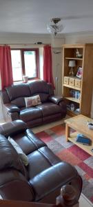 a living room with a leather couch and a table at 2 Barge Cottage in Narborough