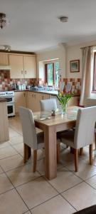 a kitchen with a wooden table and white chairs at 2 Barge Cottage in Narborough