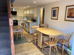 cocina y comedor con mesa de madera y sillas en The Shed, en Long Stratton