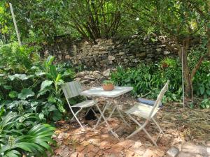 a table and two chairs in front of a stone wall at MAEVE Suíte Campo in Goiás