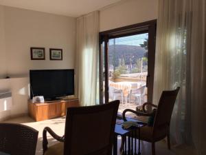 een woonkamer met een televisie en een tafel met stoelen bij STUDIO PILOT in Izmir