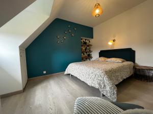 a bedroom with a bed and a blue wall at Gîte du Cosquer in Landudec