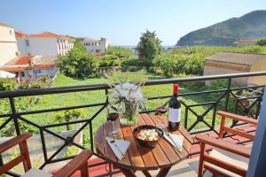 a table with a bottle of wine and a bowl of flowers at Rania Residence in Skopelos Town