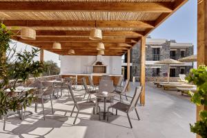 a patio with tables and chairs under a wooden pergola at Volta Suites and Villas in Gouves