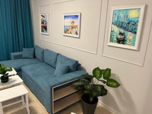 a living room with a blue couch and a plant at TM Panorama Beach Apartments in Nesebar