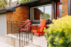 two red chairs sitting on a porch of a house at By The Vines in Niagara-on-the-Lake