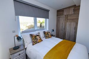 um quarto com uma cama branca com almofadas e uma janela em Aghadoe Lodge em Killarney